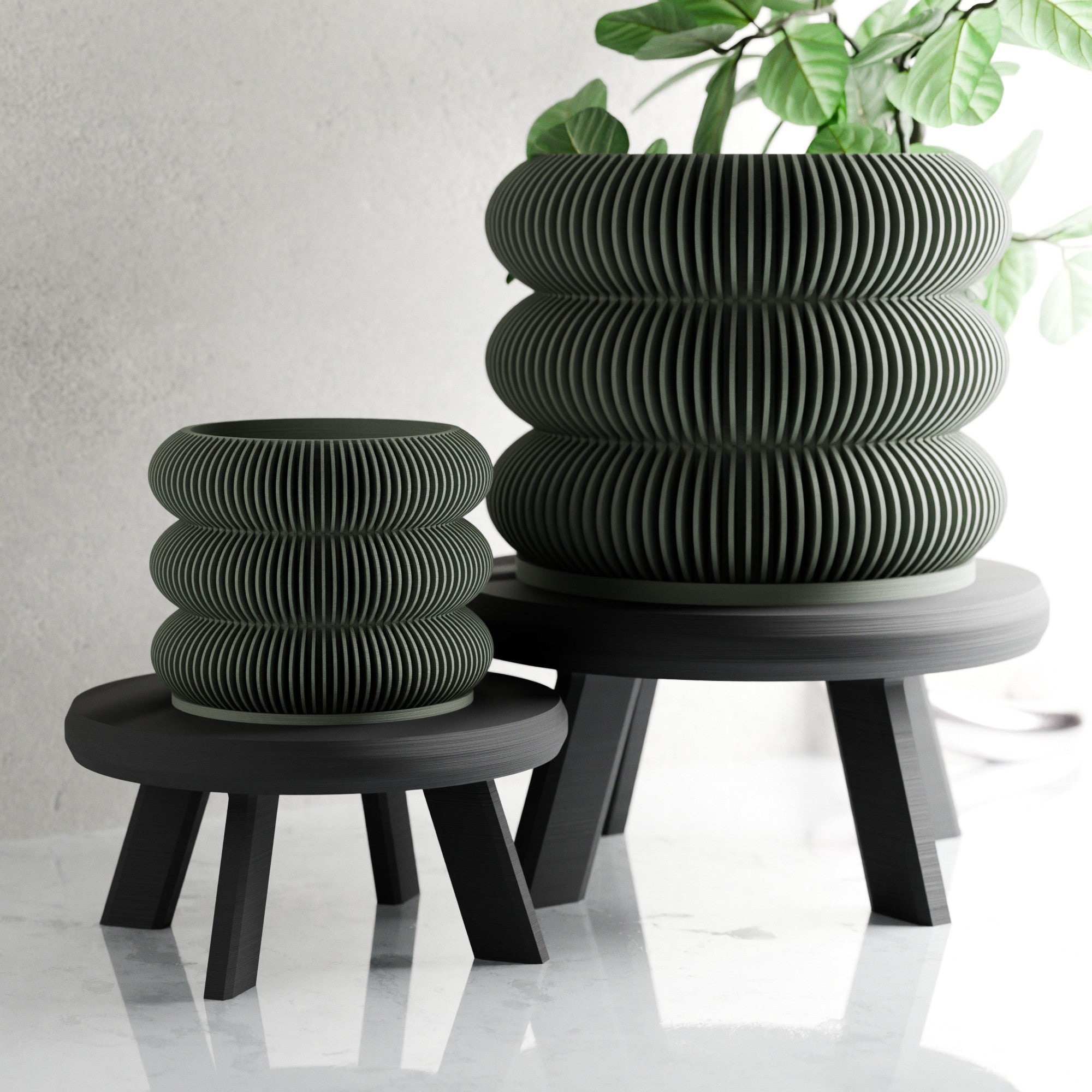 Two black ribbed planters on stands with a plant in the background.