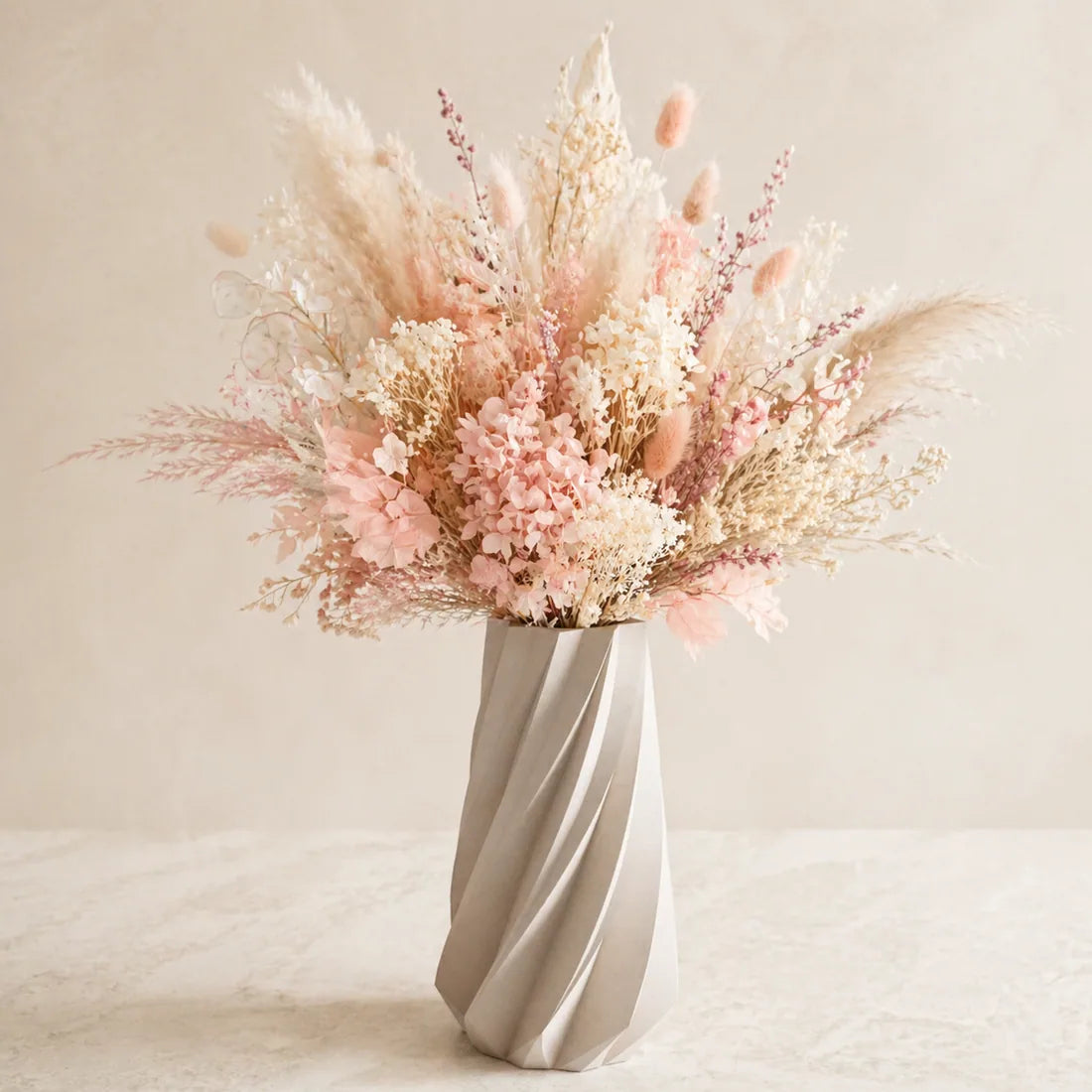 Pink dried floral arrangement in sculptural vase